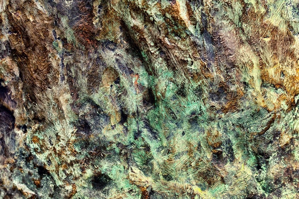 "Natos Whisper": Macro photograph of oxidized and scraped metal surfaces in copper-green and brown tones, evoking the gentle movement and ethereal essence of wind.