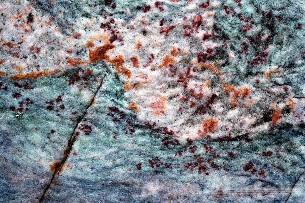 Red autumn leaves blow through a rocky mountain landscape under a cold blue sky.