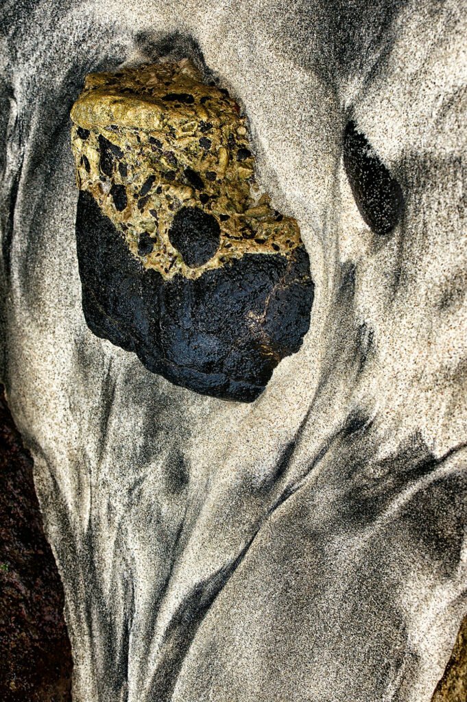 A lion-like, imaginary figure seems to emerge from volcanic ash, sand, and stone on a Balinese shore – a silent guardian beneath the shadow of Mount Gunung Agung.